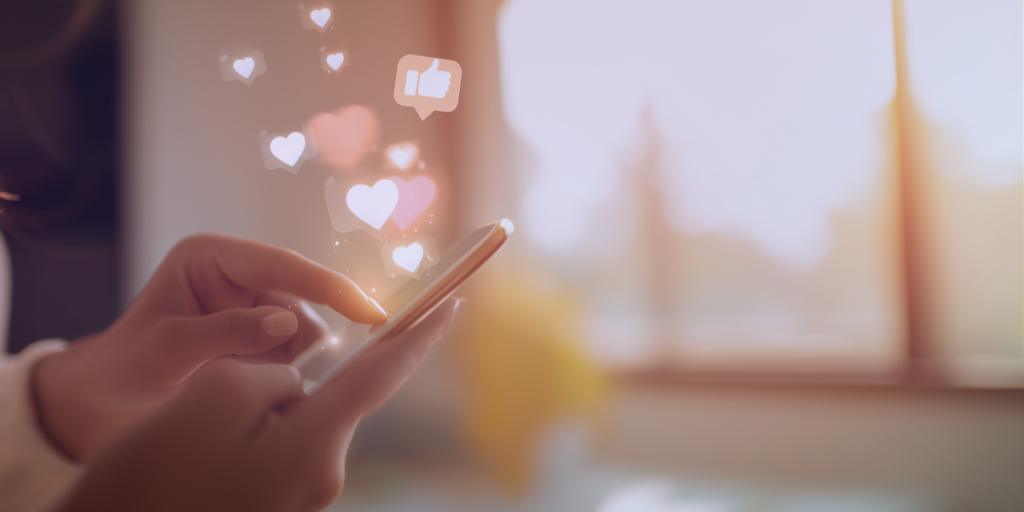 Person using smartphone with floating heart and like icons, representing social media engagement and influencer impact.